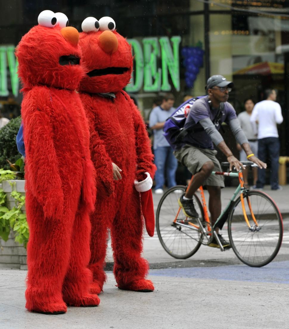 Two Elmos wait to pose for pictures with tourists in Times Square.